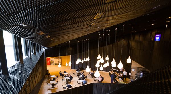 The MCK foyer with café tables under hanging teardrop-shaped lamps